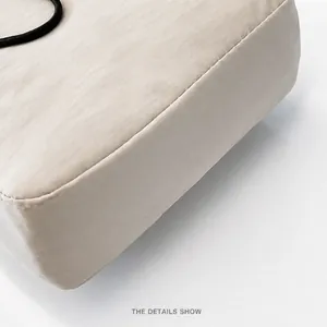 Dettaglio ravvicinato della borsa a tracolla in nylon crema con cuciture e bordo nero