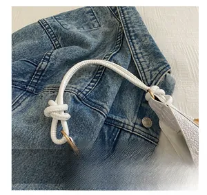 Detailed close-up of white crocodile embossed texture and decorative knot handle of the bag