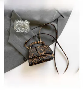 Detail view of mini leopard print crossbody bag with top handle and magnetic strap buckle