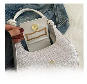 Detail view of the magnetic metal buckle and embossed crocodile texture on white handbag