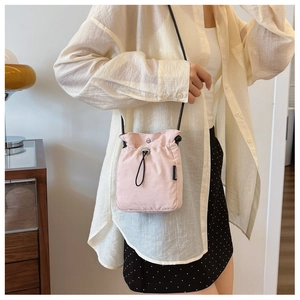 Dettaglio della mini borsa a tracolla rosa chiaro con coulisse e tracolla nera
