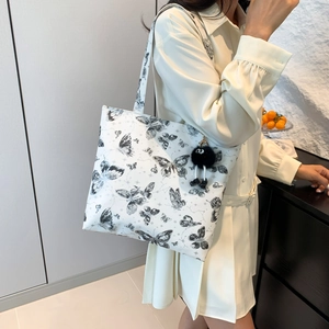 Stijlvolle witte tote bag met vlinderprint en hanger, getoond door een model in stijl