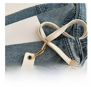 Détail de la bandoulière en cuir blanc avec fermoir en métal doré et boucle réglable