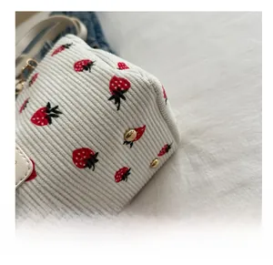 Vue détaillée du fond de sac en velours côtelé blanc avec motif fraise et clous dorés