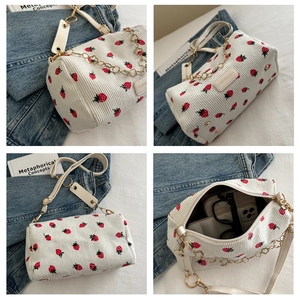 Détail du sac cylindrique en velours blanc avec broderie fraise et chaîne dorée