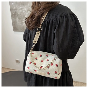Detail of strawberry embroidery on beige corduroy bag with gold chain strap detail