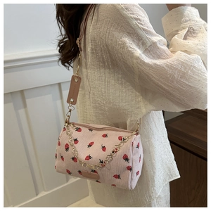 Detail of pink corduroy shoulder bag featuring strawberry print and gold floral chain