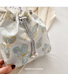 Detail of blue silk jacquard bucket bag with butterfly pattern and pearl chain