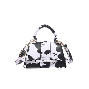 Mini bolso de mano con estampado de vaca en blanco y negro y herrajes dorados en blanco