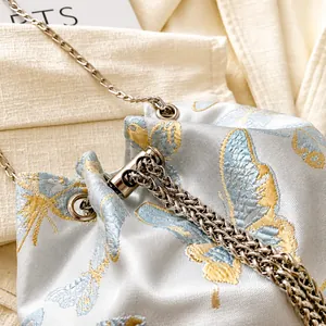 Detail of silk bucket bag showing exquisite butterfly embroidery and silver metal chain
