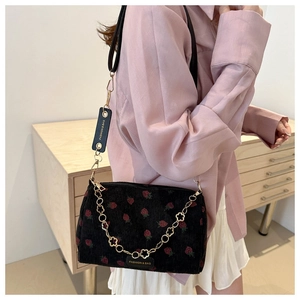 Detail der Cord-Schultertasche mit Erdbeerdruck, goldener Blumenkette und Lederriemen