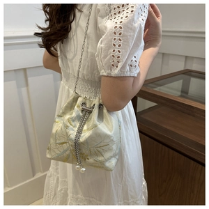 Detail of embroidered jacquard bucket bag with silver chain and pearl drawstring charms
