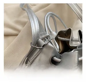 Detail of silver bucket bag showing drawstring closure and shiny round metal hardware