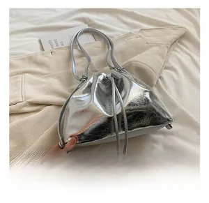 Close-up of a metallic silver bucket bag with drawstring closure and glossy pleated texture