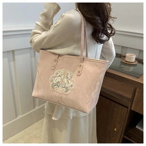 Détail du sac cabas rose en toile avec broderie florale et rivets dorés sur l'anse