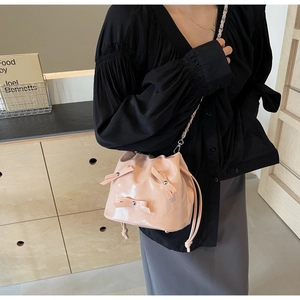 Détail du sac seau rose en cuir verni avec nœuds mignons et bandoulière chaîne argent