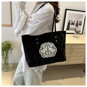 Vue détaillée d'un sac cabas noir avec broderie florale raffinée et texture plissée élégante