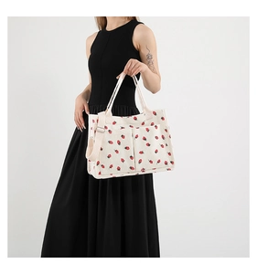 Detailed side view of white corduroy tote bag with red strawberry pattern on a model