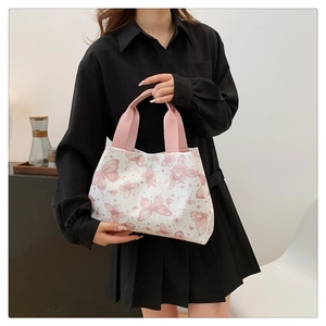 Détail de l'imprimé papillon rose sur un sac cabas blanc tenu par un mannequin en robe