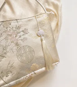 Detailed view of Chinese style silk jacquard bag with white lotus and tassel pendant