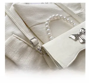 Detail of adjustable metal buckle and detachable strap on white bow-knot crossbody bag