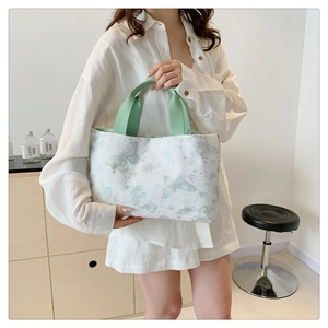 Détails des motifs papillon turquoise et sangles en toile sur un grand sac à main