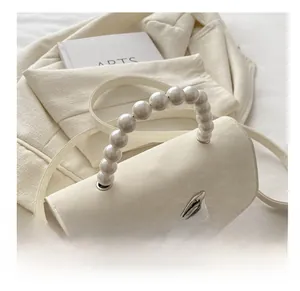 Detail of cream white leather bag featuring pearl handle and silver bow buckle