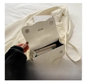 Detail view of cream textured crossbody bag with dual magnetic buckles and phone capacity