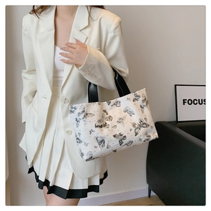 Détail d'un grand sac fourre-tout en toile blanche avec motifs de papillons et anses noires
