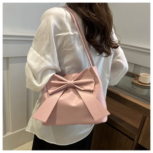 Detalle del bolso tote rosa claro con lazo grande y acabado de cuero sintético brillante
