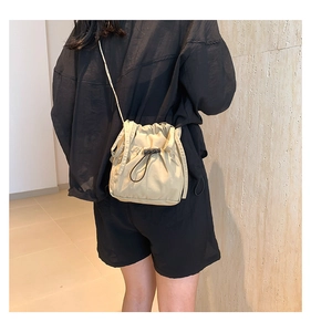 Dettaglio indossato di una borsa a tracolla in nylon beige con coulisse pieghettata