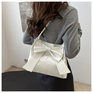 Zijaanzicht van de crèmewitte tote bag met strik gedragen door een model in kamer