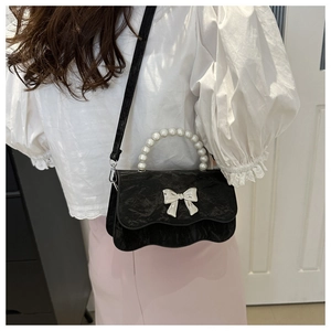 Detail of black velvet bow bag with pearl handle and silver wave edge flap