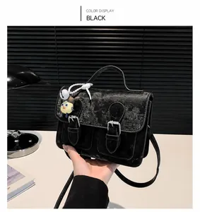Dettaglio della borsa postino retrò nera con texture opaca e fibbie argentate in un ufficio
