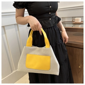 Detail der grauen Canvas-Tasche mit kontrastierender gelber Ledertasche und Griff
