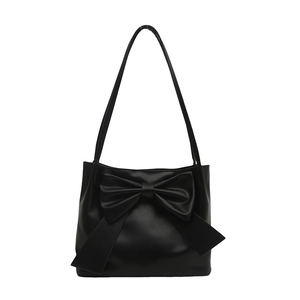 Minimalist black bow tote bag in matte synthetic leather with large decorative ribbon accent