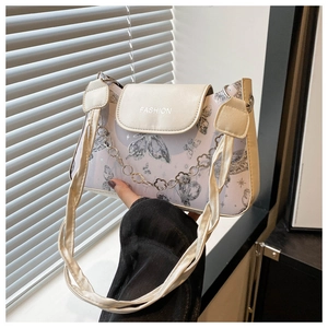 Detail of cream crossbody bag with lavender butterfly prints and petal-shaped chain