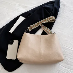 Close-up of beige lychee leather tote bag featuring a bohemian geometric woven wide strap