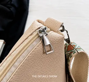 Detail of cream lychee leather tote with silver zipper and boho woven shoulder strap