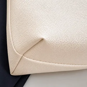Detail shot of beige leather tote bag featuring lychee grain texture and precision stitching