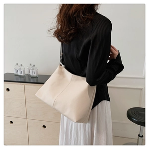 Detailed view of off-white lychee texture shoulder bag styled by a model in casual setting