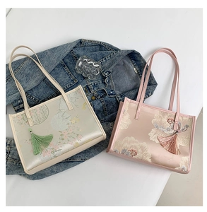 Detalle de bordado floral tradicional y borlas de seda en bolsos tipo tote de estilo chino