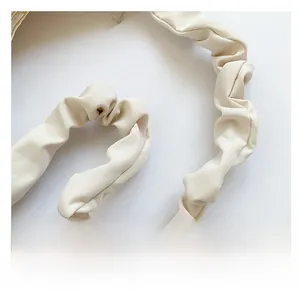 Detailed view of beige pleated shoulder strap with a soft cloud-like ruffled design