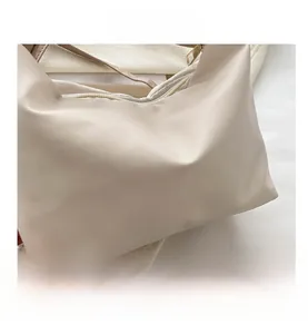 Detail view of cream-colored pleated handbag featuring a smooth zipper and leather texture