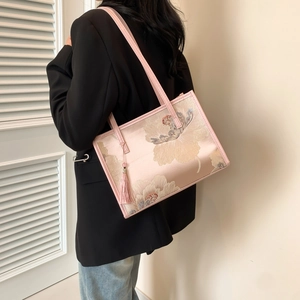 Bolso de mano bordado con flores rosas y textura de seda llevado por una modelo elegante