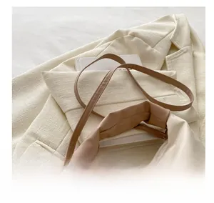 Detail of adjustable leather strap and pleated texture on cream crossbody bag