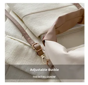 Close-up of adjustable metal buckle and leather strap on a cream pleated shoulder bag