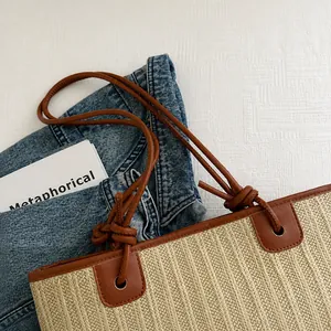 Detail der geflochtenen Strohtasche mit braunen Leder-Schultergurten und genähter Kante