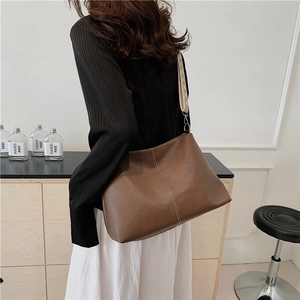 Retro brown leather underarm bag with ethnic woven strap shown on a model's shoulder