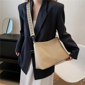 Minimalist beige leather shoulder bag with ethnic geometric wide strap shown on model